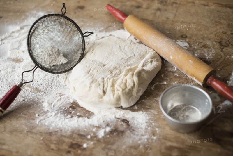 Rolling pin, Strainer and dough on kitchen counter.