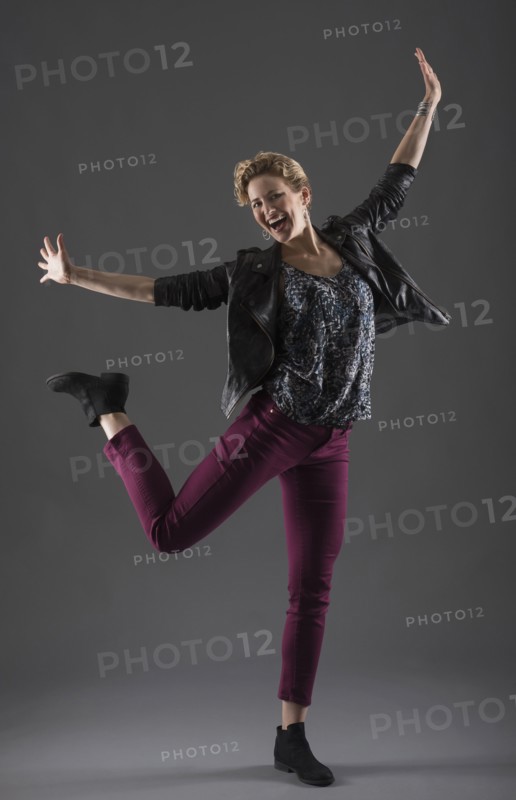 Studio shot of cheerful woman with arms raised.