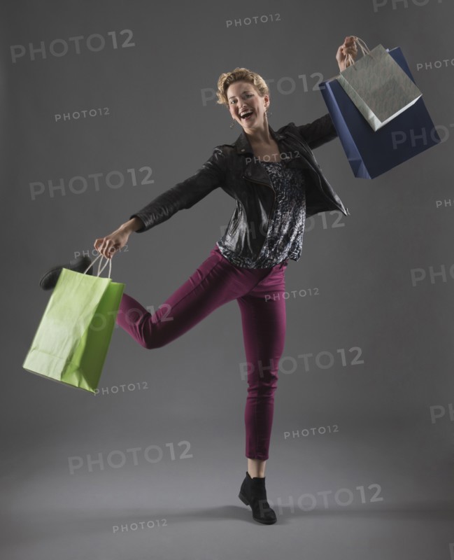 Studio shot of cheerful woman holding shopping bags.