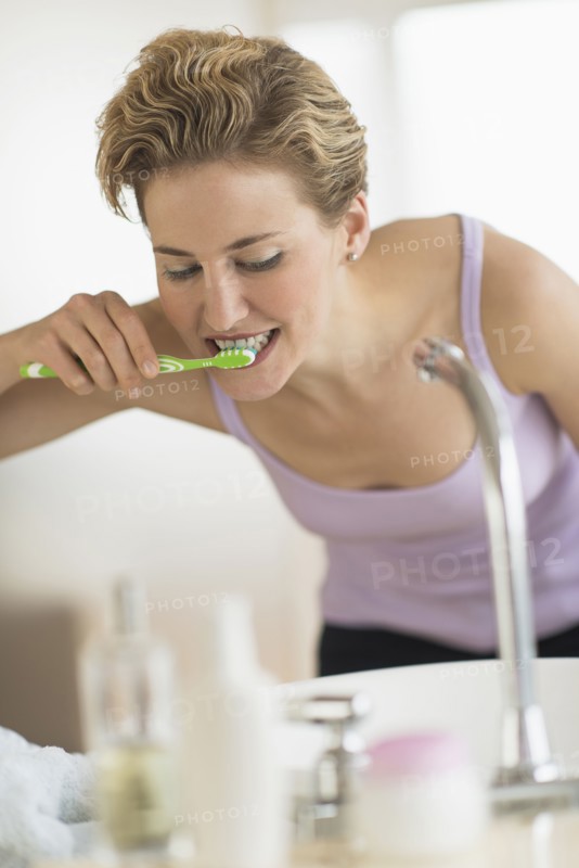 Young woman brushing teeth in bathroom.