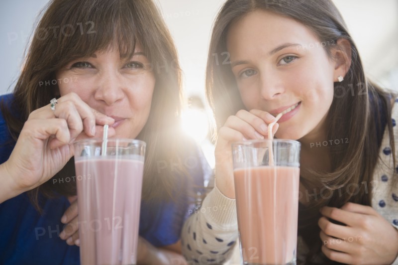 Portrait of mother and daughter (14-15) drinking milkshakes