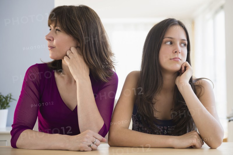 Frustrated teenage girl (14-15) and her mom sitting at table
