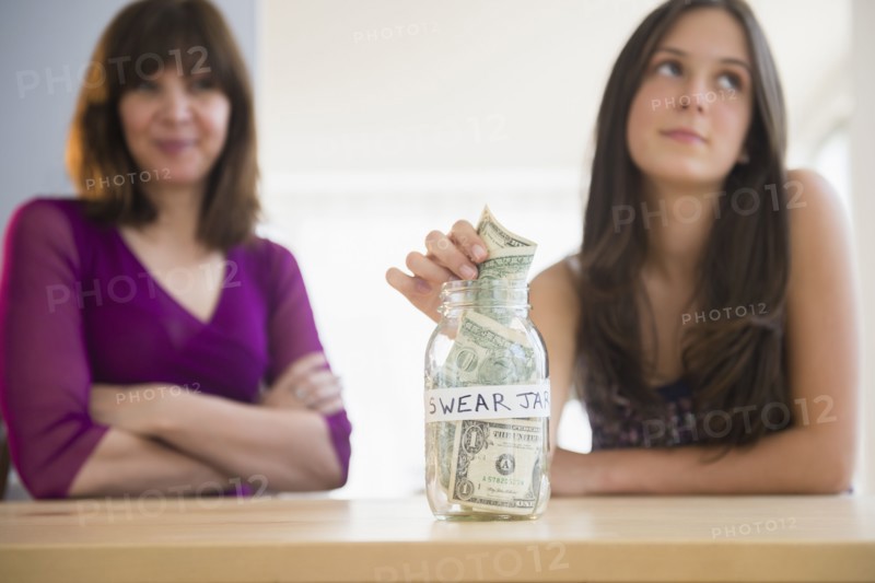 Teenage girl (14-15) putting money in swear jar