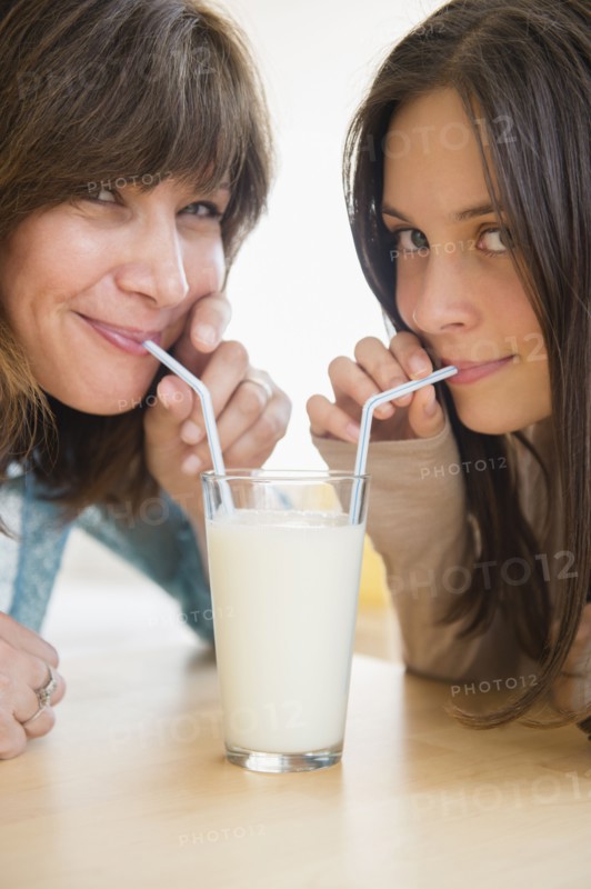 Teenage girl (14-15) drinking milk with her mom at home