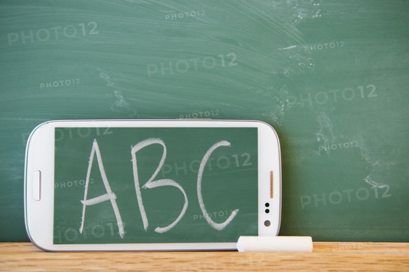 Smartphone leaning against chalkboard with ABC letters displayed