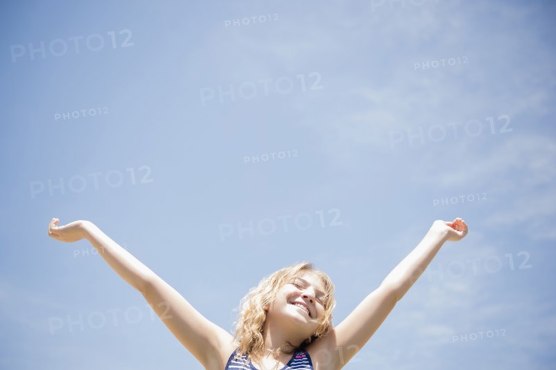 Girl (12-13) with arms raised, smiling