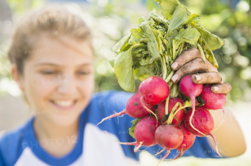 Girl (12-13) showing bunch of radish