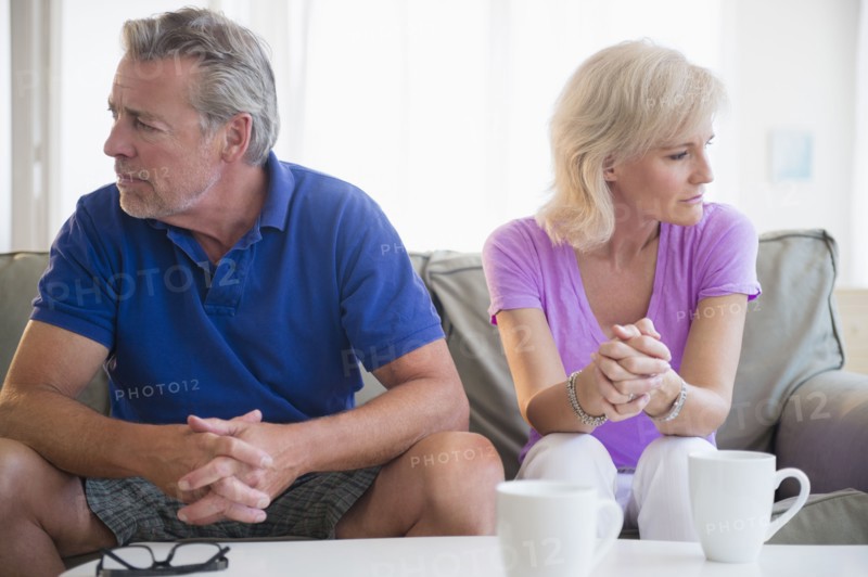 Portrait of couple sitting on sofa, looking away from each other