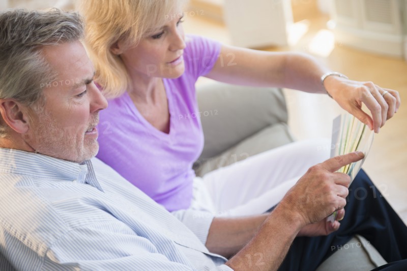 Portrait of couple sitting on sofa looking at sheet of paper