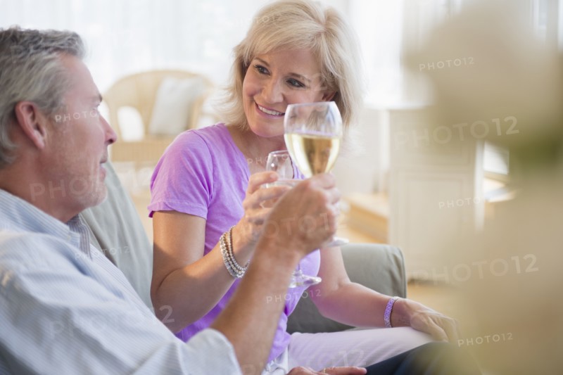 Portrait of couple sitting on sofa drinking white wine