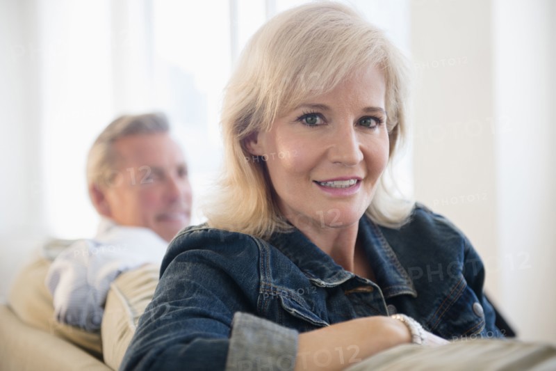 Portrait of woman wearing denim jacket sitting on sofa