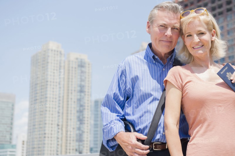 Portrait of couple with passport against skyscrapers