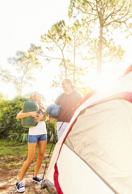 Couple standing next to tent in forest