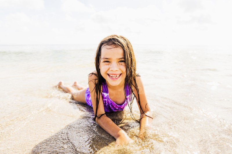 Portrait of girl (6-7) lying in sand on beach