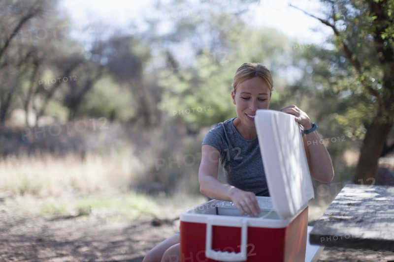 Smiling woman opening cooler in park