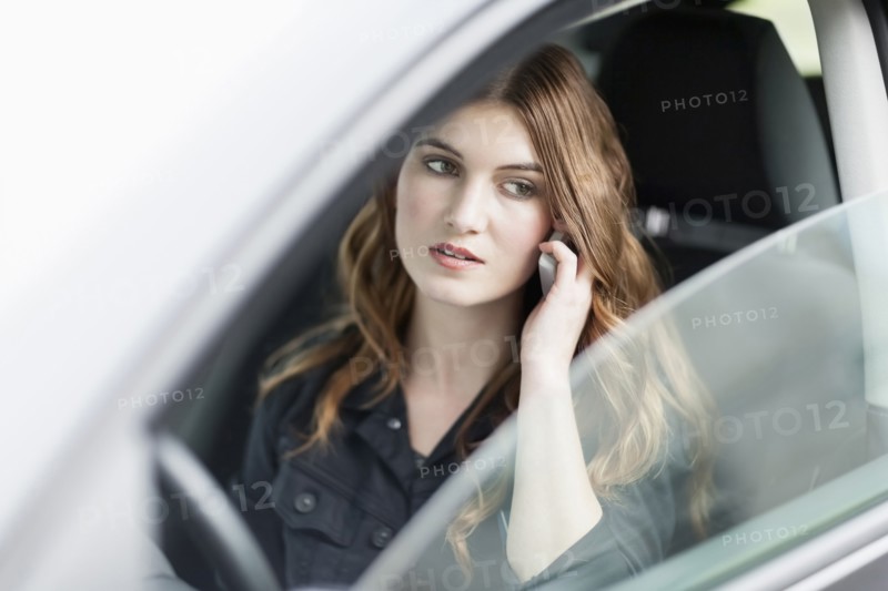 Young woman speaking on phone in car