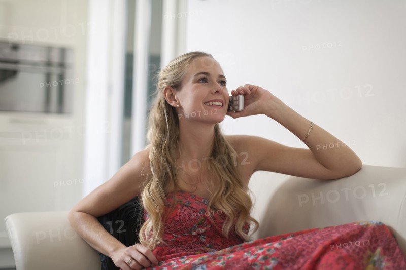 Woman in dress sitting on sofa and using phone