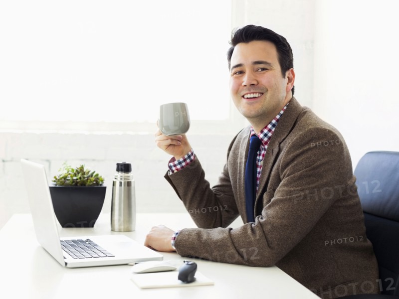 Portrait of businessman sitting in office and drinking coffee