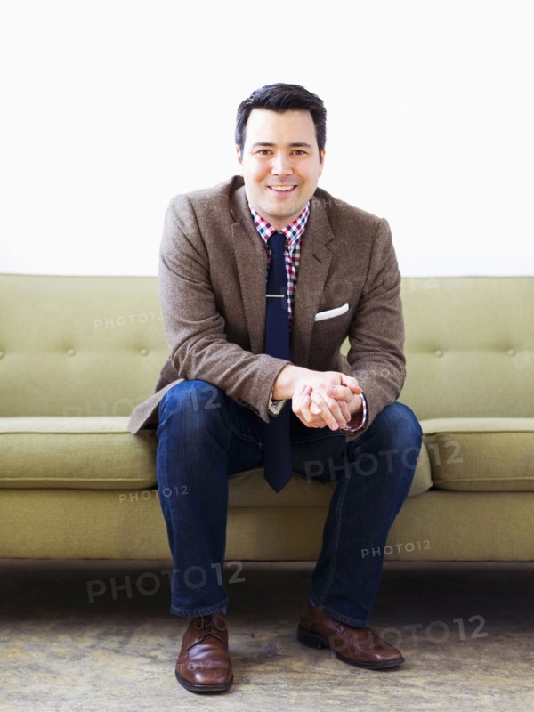 Man in suit sitting on sofa and posing to camera