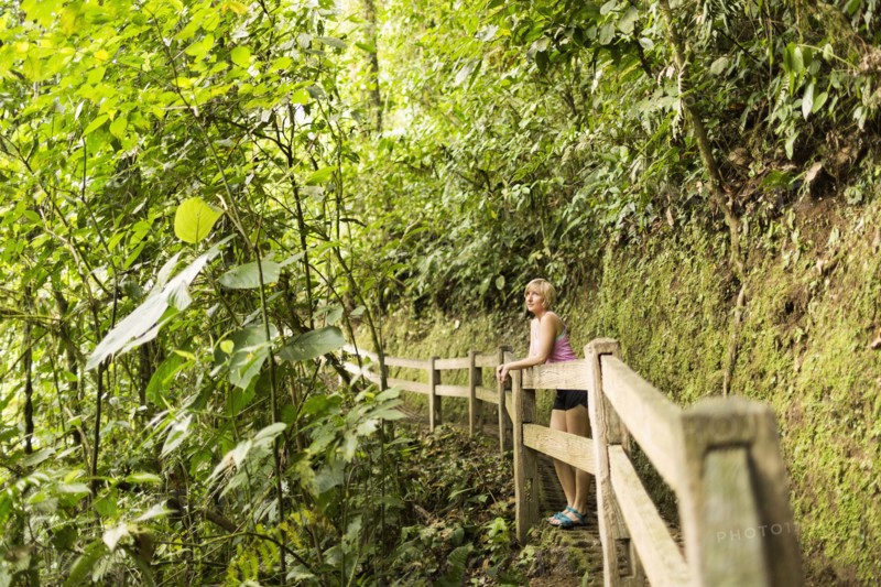 Woman in forest leaning against wooden fence
