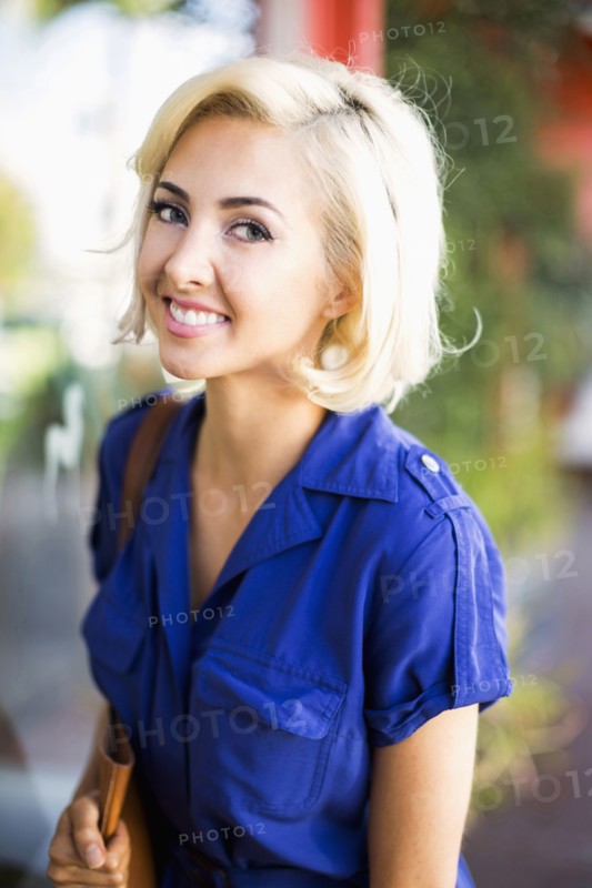 Woman with dyed hair and wearing blue dress looking at camera