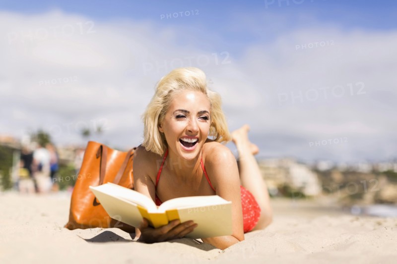 Portrait of blond woman reading book on beach