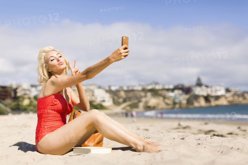 Blond woman taking selfie on beach