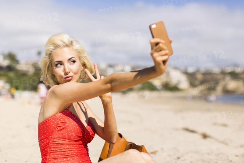 Blond woman taking selfie on beach