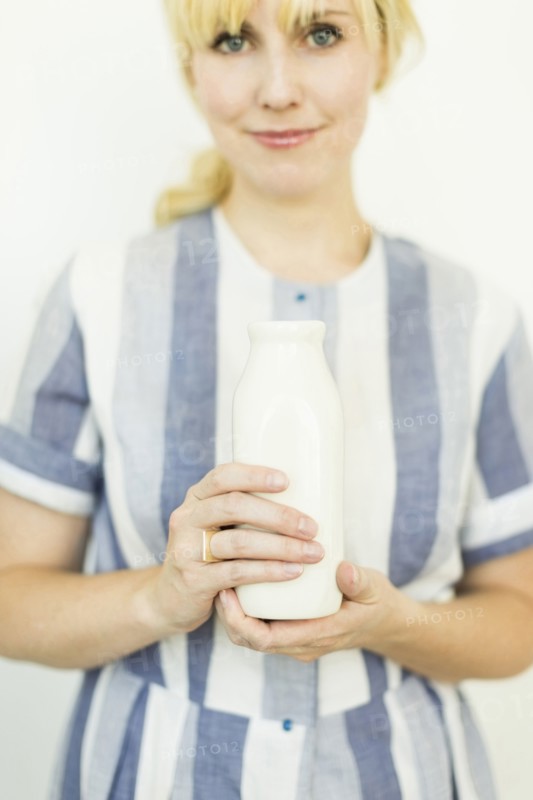 Studio shot of woman holding milk bottle