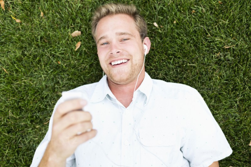 Portrait of young man listening to music in park