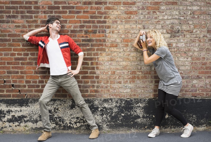 Woman taking pictures of man.