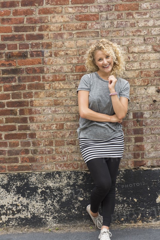 Portrait of young woman in front of brick wall.