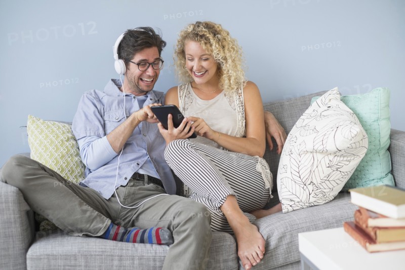 Couple sitting on sofa listening to music.