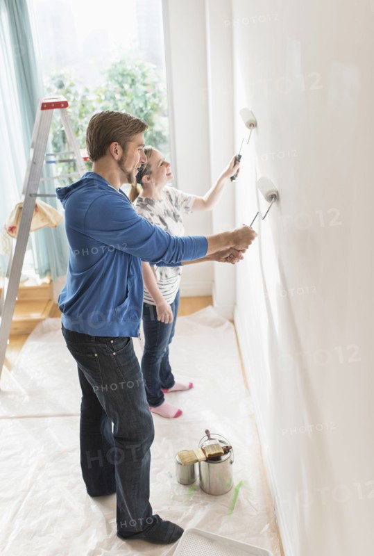 Smiling couple painting wall.