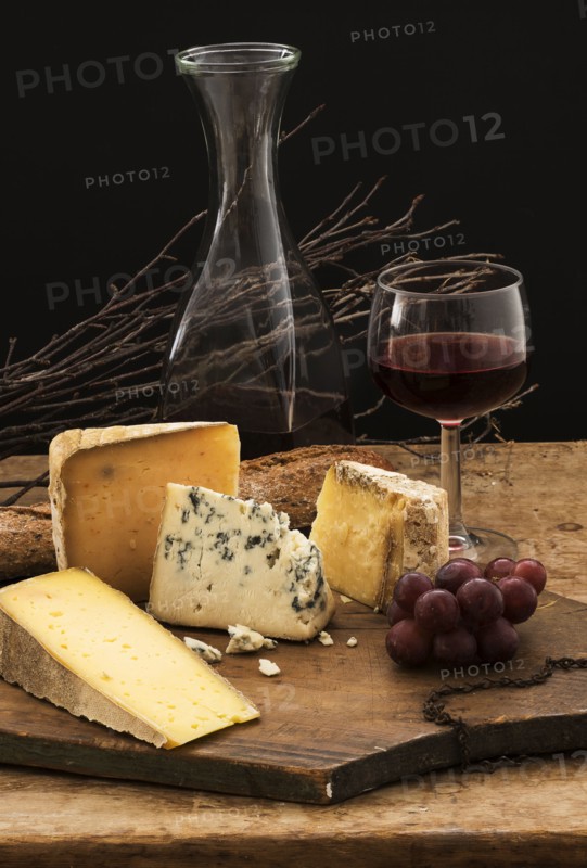 Still life with cheese and red wine on wooden table, studio shot.