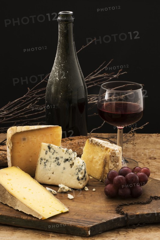Still life with cheese and red wine on wooden table, studio shot.
