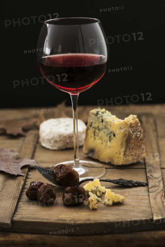 Still life with cheese and red wine on wooden table, studio shot.