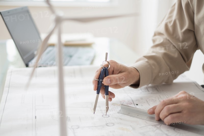 Close up of man's hands using compass while drawing plans.