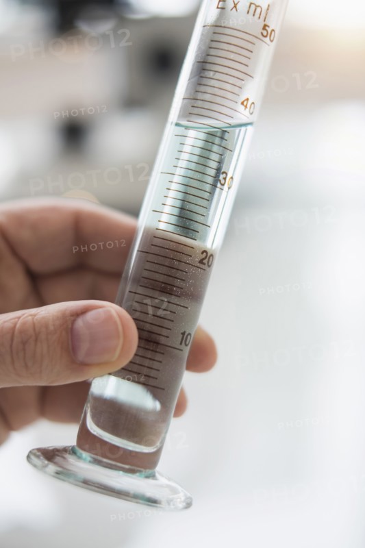 Close up of man's hand holding test tube with liquid.