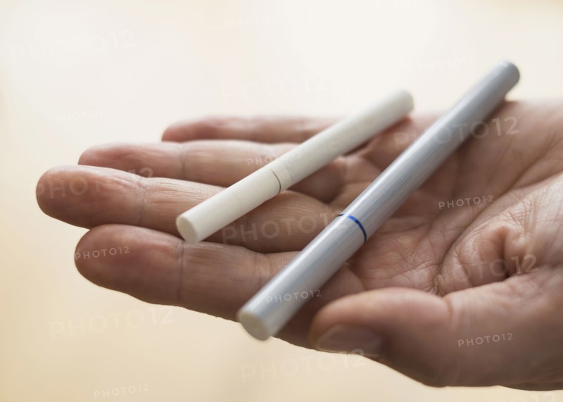Close up of man's hand holding cigarette and e-cigarette.