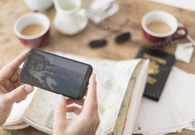 Close up of man's hand holding smartphone above map.