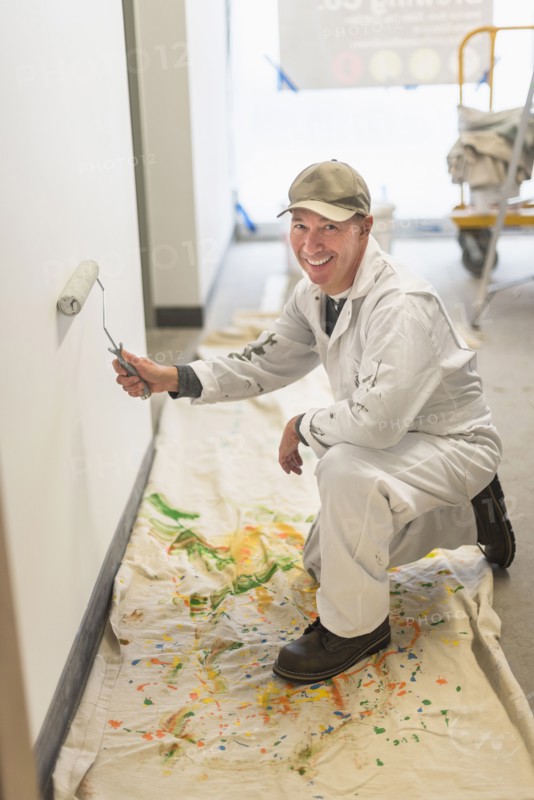 Portrait of smiling manual worker painting wall.
