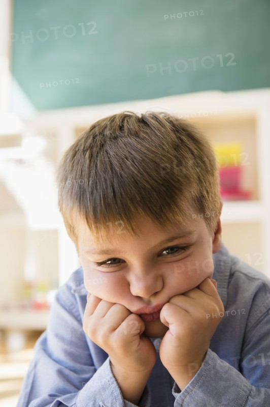 Portrait of frustrated boy (6-7) sitting in classroom