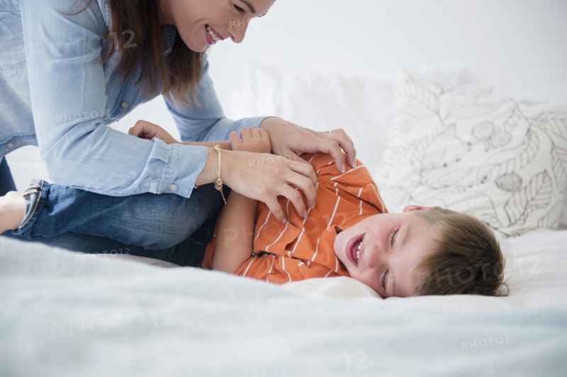 Mother and son (6-7) playing in bed