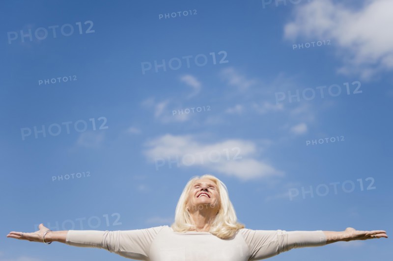 Upward view of senior woman with arms outstretched