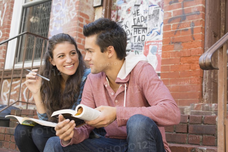 Young couple reading book and doing crossword