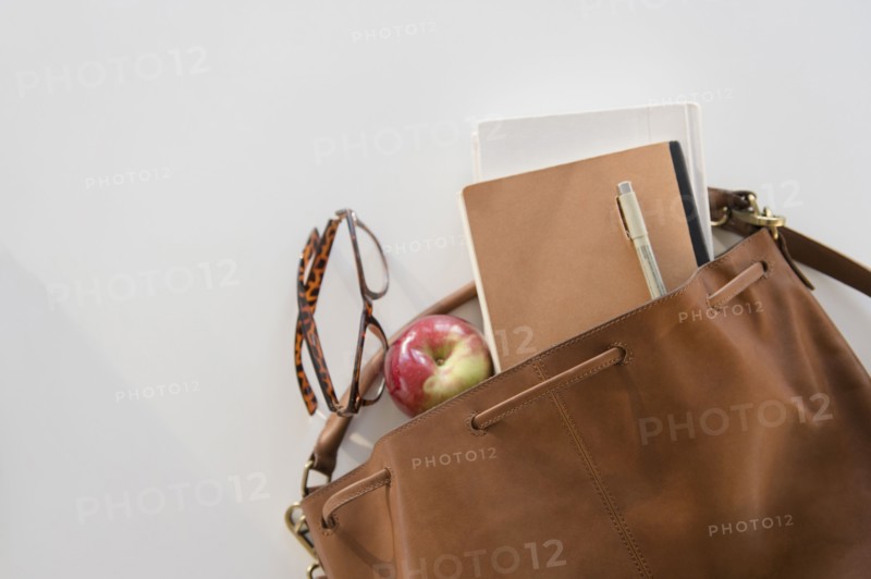 Studio Shot of shoulder bag with apple and notebook in it