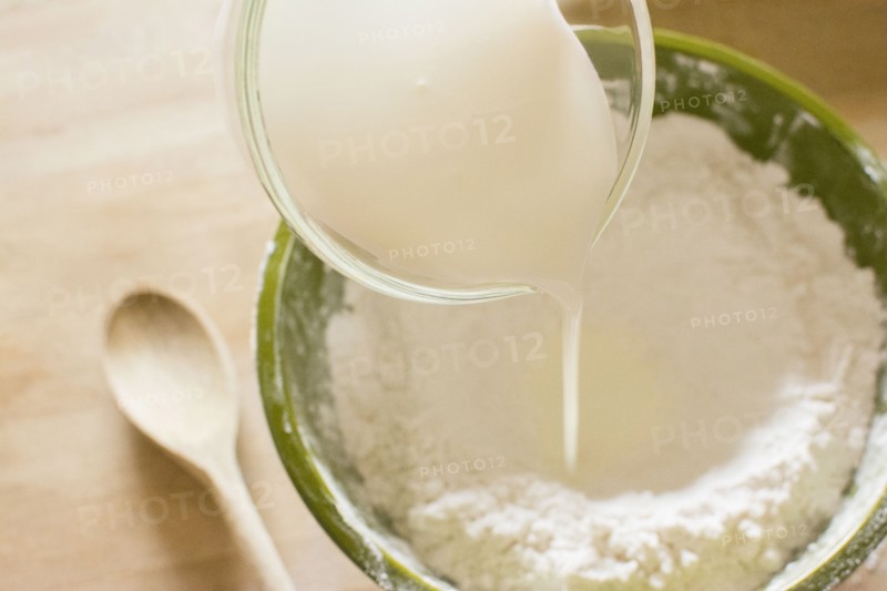 Pouring milk into bowl with flour