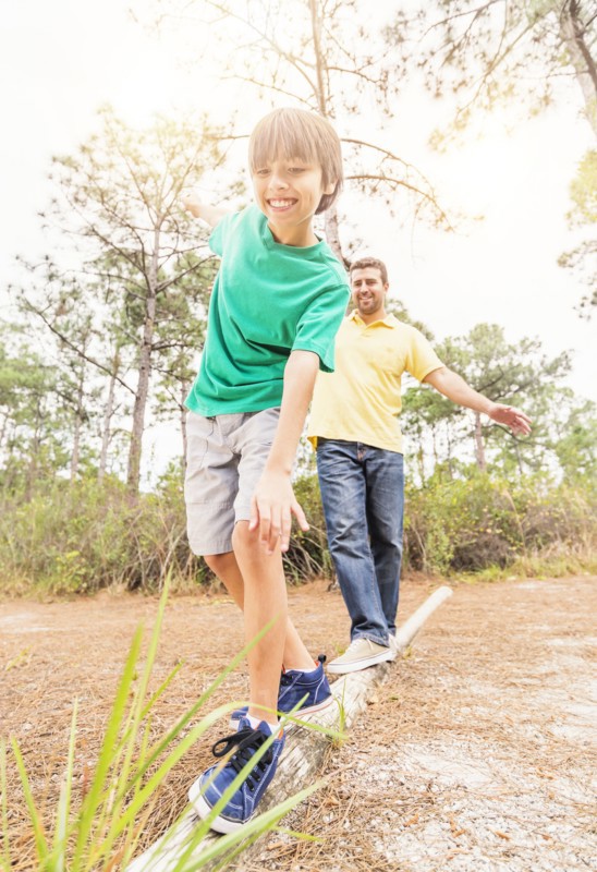 Father and son (12-13) balancing on log