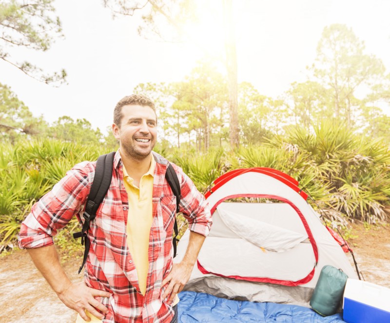 Man with backpack in front of tent